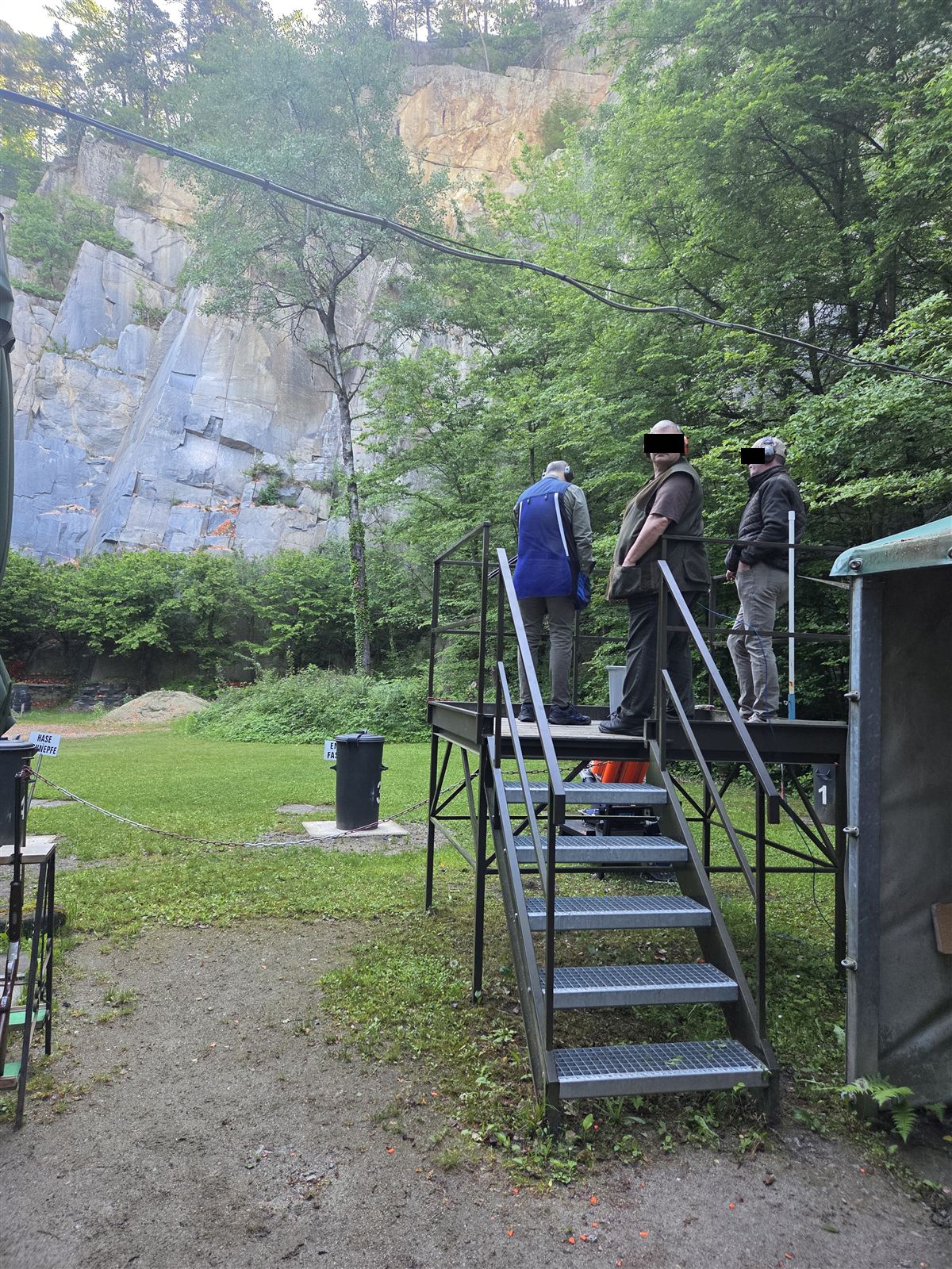 Prüflinge mit Gehörschutz auf dem Schützenstand im Steinbruch, im Hintergrund eine hohe Felswand